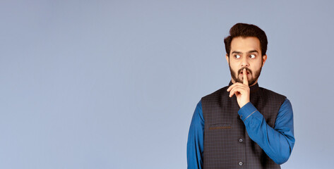 Attractive Indian man showing silence gesture over lilac background. Panorama