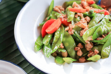 Stir Fried Green Peas with pork and carrot in vintage metal white plate. Homemade food Thai style