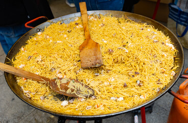 Large paellera with delicious traditional Valencian seafood fideua, savory noodle dish with shrimps...