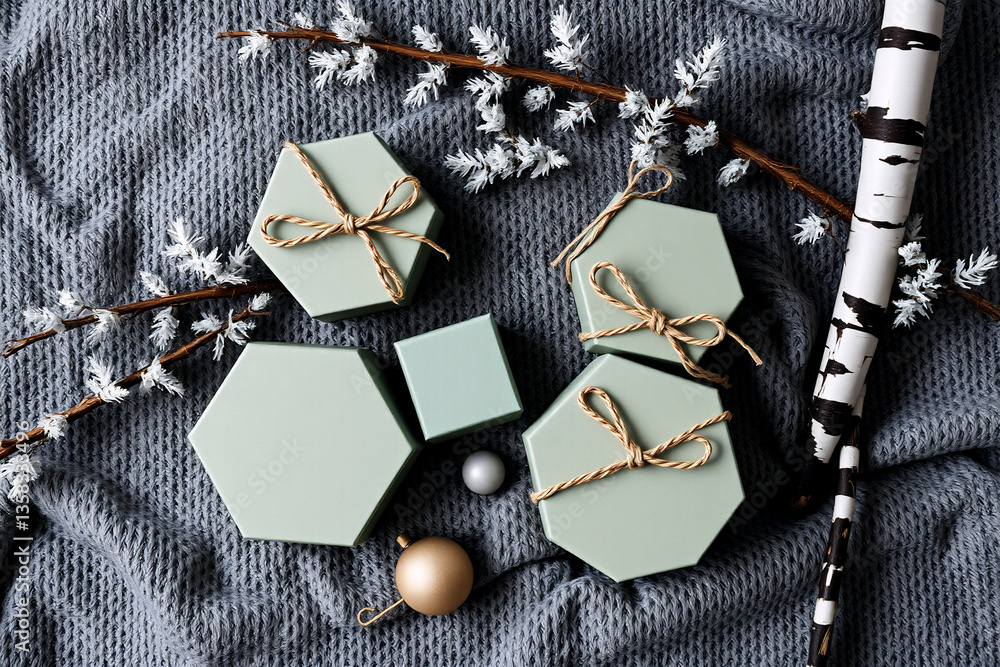 Poster hexagonal gift boxes with string bows and ornaments arranged with birch branch on grey knitted blank