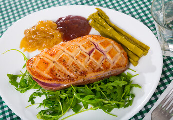 Juicy roasted moulard duck magret served with caramelized onions, berry sauce, pickled asparagus and fresh greens