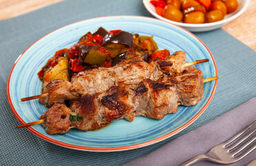 Traditional oriental grilled pork meat shashlik served with sauteed aubergines and tomatoes