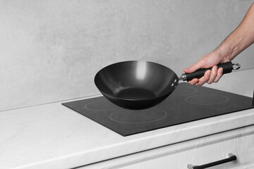 Chef with frying pan over cooktop in kitchen, closeup. Space for text