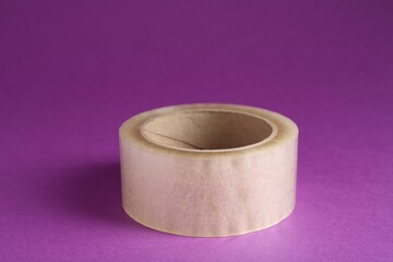 Roll of adhesive tape on violet background