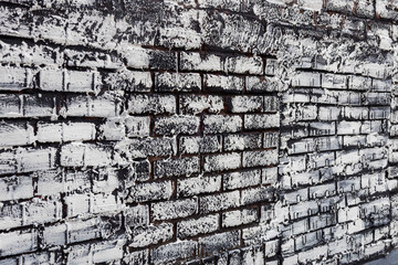 Full frame abstract texture background of a vintage brick wall that has been updated with a German smear painting technique, allowing the dark original color to show through the white painted overcoat