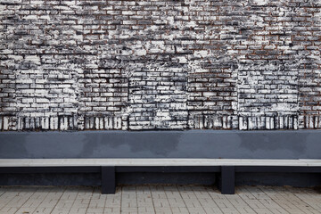 Full frame abstract texture background of a blueish gray wooden bench along a vintage brick wall that has been updated with a German smear painting technique