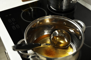Used cooking oil and ladle in saucepan on stove