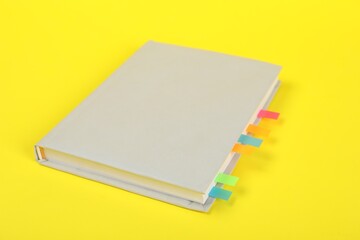 Book with colorful tabs on yellow background, closeup