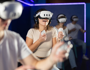 In dark hall of entertainment center, young guys and girls talking about spending time in virtual...