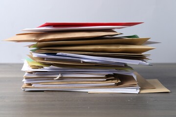 Stack of different paper envelopes on wooden table, closeup. Post office