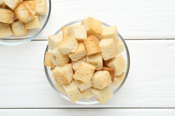 Delicious crispy croutons on white wooden table, top view