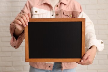 Woman holding blank small blackboard indoors, closeup