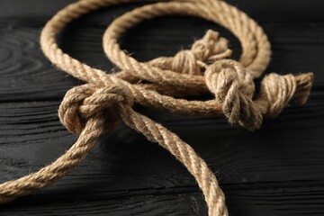 Cotton rope with knot on black wooden background, closeup