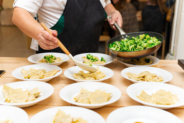 Chef plating ravioli with sautéed broccoli.