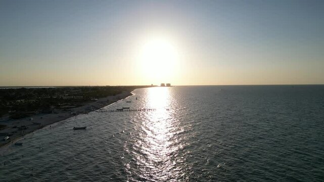 sunset view of progreso beach with pelicans diving into the water and new construction buildings in the background (scenic dusk night birds swimming boats in ocean gulf of mexico) travel tourism bird
