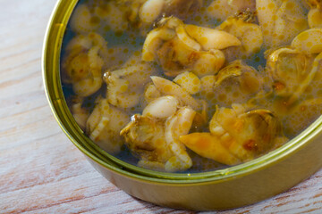 Open tin can with white clams on wooden background