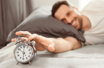 Good Morning. Happy Well-Slept Man Turning Off Alarm-Clock Waking Getting Up Lying In Bed At Home....
