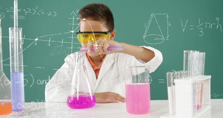 In school, young boy in lab coat conducting science experiment with test tubes
