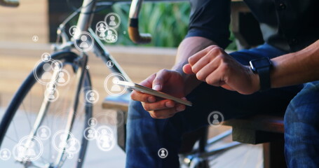Fototapeta premium Using smartphone with social media icons, man staying connected near bicycle outdoors