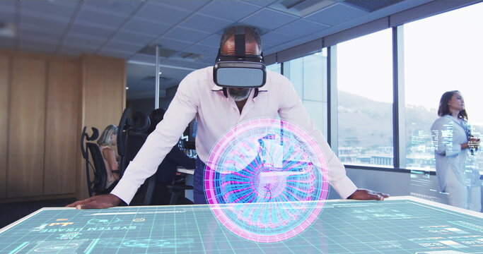 Businessman using VR headset interacting with holographic display in modern office