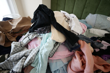 Clothing pile on bed disorganized during spring cleaning process