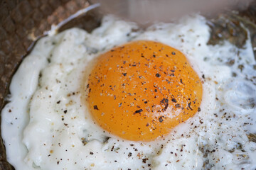 Brightly cooked egg with seasonings on a textured plate