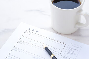 就職活動（就活）のために、コーヒーを飲みながら、履歴書を作成する
