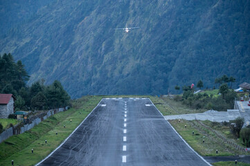 Obraz premium An aircraft before landing on the runway in Lukla airport the most dangerous airport in the world in Nepal. The runway rests on a hillside in the town of Lukla, Nepal.