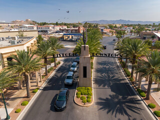 Aerial view of cars driving under the "Historic Downtown" sign in Boulder City, Nevada, USA. Palm trees line the street, leading to shops and businesses. © Zenstratus