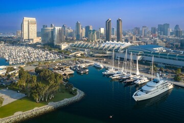 Aerial view of San Diego Bay in California, USA. Yachts are docked in the foreground at Fifth Avenue Landing, with the city skyline and convention center visible in the background.