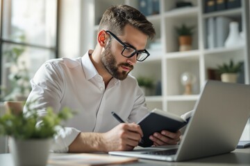 Fototapeta premium Focused businessman working at desk with laptop and notebook.