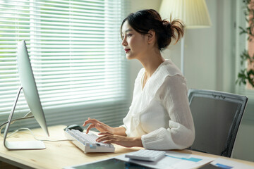 A woman is sitting at a desk with a computer monitor