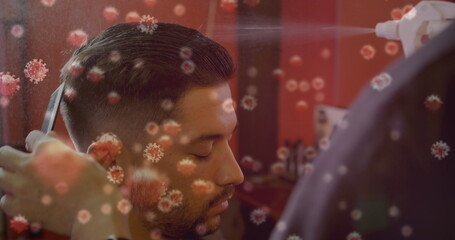 Man getting haircut while barber sprays disinfectant, virus particles overlay