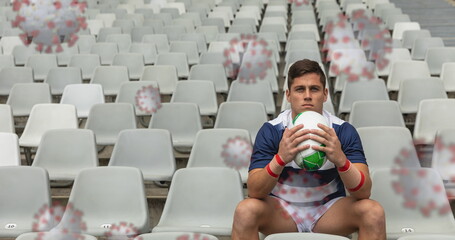 Image of cells floating over caucasian male rugby player with a ball sitting on empty stadium