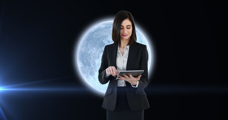 Image of woman using tablet over planet earth with glowing spot of light