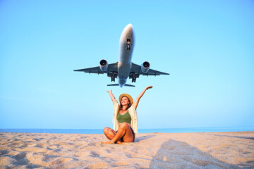 Happy satisfied smiling cheerful joyful traveler girl with open arms watching airplane flying overhead