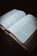 The Holy Bible book opens to The Book of Ecclesiastes with a bright light on a black background.