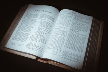 The Holy Bible book opens to The Book of Ecclesiastes with a bright light on a black background.