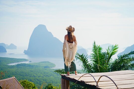 Free boho woman traveler standing on wooden bridge enjoying picturesque nature landscape, traveling to beautiful destination at Samet Nangshe, Thailand