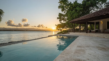 Fototapeta premium tranquil sunset view over serene ocean shore, featuring luxurious pool and beautiful villa. warm colors of sky reflect on water, creating peaceful atmosphere