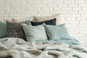 Cozy bedroom pillows & throws on a bed against white brick