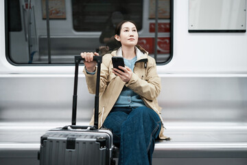 Young Traveler Relaxing in Subway with Smartphone and Luggage