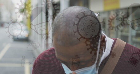 Image of covid 19 icons over african american man sneezing wearing face mask