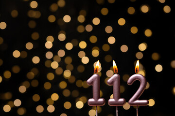 Birthday candle with number on blurred background with lights