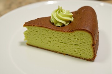 A Delicious Slice of Green Tea Cake Displayed on a White Plate, Showcasing its Fluffy Texture and Delicate Frosting on Top, Perfect for Dessert Lovers