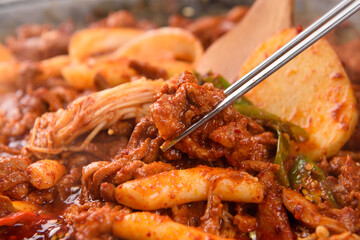 A picture of someone lifting spicy duck bulgogi with chopsticks