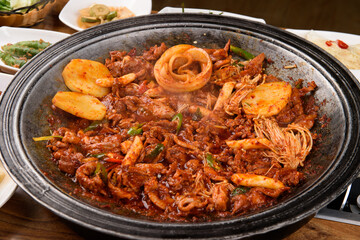 Spicy marinated duck bulgogi and various side dishes on a pot lid brazier