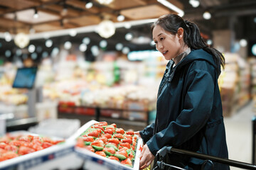 Joyful Shopper Choosing Fresh Strawberries in Vibrant Grocery Store