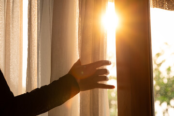 woman's hand She opened the curtains on the window. There was morning light through the window in...