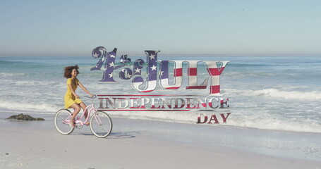 Image of 4th of july independence day text with american flag pattern and woman on bike on beach